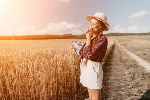Woman farmer walks through a wheat field at sunset, touching green ears of wheat with his hands. Hand farmer is touching ears of wheat on field in sun, inspecting her harvest. Agricultural business.