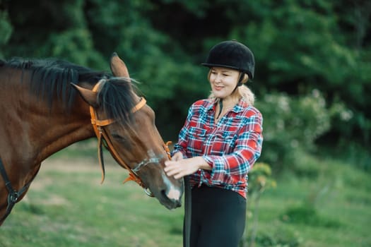 Happy blonde with horse in forest. Woman and a horse walking through the field during the day. Dressed in a plaid shirt and black leggings
