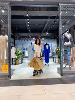 Shopping woman, women's fashion clothes in a store, boutique. Woman choosing clothes in a store.