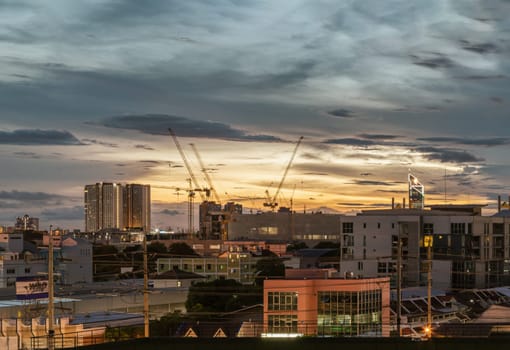Bangkok, Thailand - Aug 14, 2024 - Night city view of Construction of tall buildings with a crane and background of Dramatic sky in the city of Bangkok. Tower crane, Construction cranes, Construction and urban development. use it as your Wallpaper, Poster and Space for text, Selective focus.