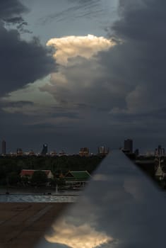 The sky is being covered with amazing clouds with reflection on stainless steel handrail with city view alongside river. Concept idea of Imaginative clouds background, Nature abstract composition for wallpaper and text, Selective focus.