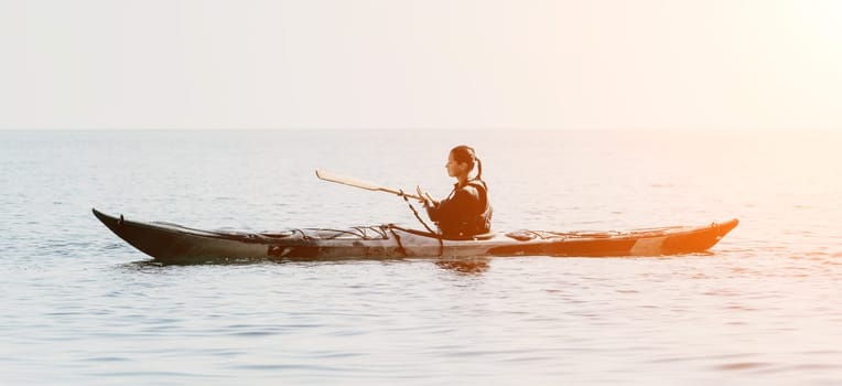 Happy smiling woman in kayak on ocean, paddling with wooden oar. Calm sea water and horizon in background