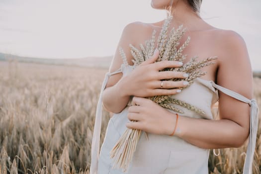 A woman in a white dress holds a bunch of wheat while standing in a field.