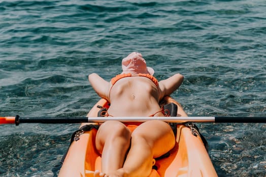 Happy smiling woman in kayak on ocean, paddling with wooden oar. Calm sea water and horizon in background