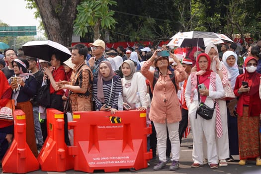 17 August 2024, Jakarta, Indonesia. The atmosphere near the Jakarta Palace during Indonesia's Independence Day is electric, filled with patriotic fervor and national pride. Crowds of people, dressed in red and white, gather to witness the flag-raising ceremony and participate in various festivities.