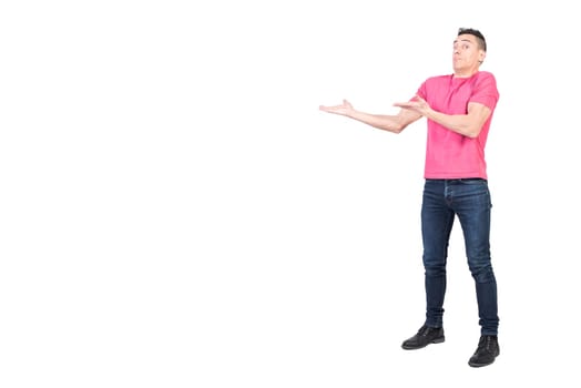 Full body of confused male model in casual outfit pointing aside and looking at camera with amazed face isolated on white background