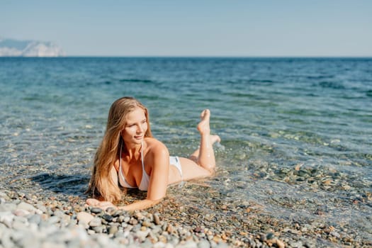 A woman is laying on the beach in a bikini, enjoying the ocean. Scene is relaxed and carefree