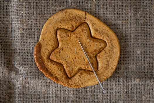 Brown sugar caramel candy cookies with a metal needle in the shape of a star. Concept of survival game