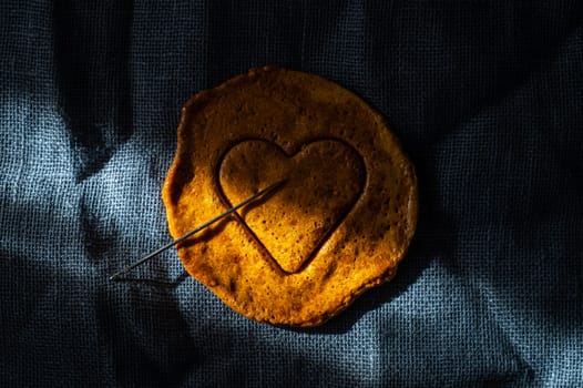 Brown sugar caramel candy cookies with a metal needle in the shape of a heart. Concept of survival game