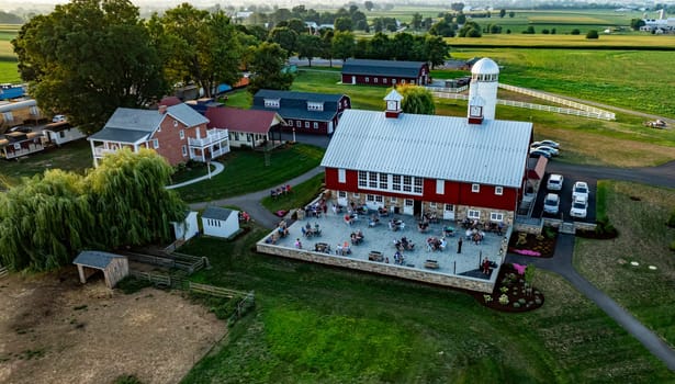 Ronks, Pennsylvania, USA, August 1, 2024 - Guests enjoy dining on the terrace of a rustic farm restaurant surrounded by lush fields at dusk.