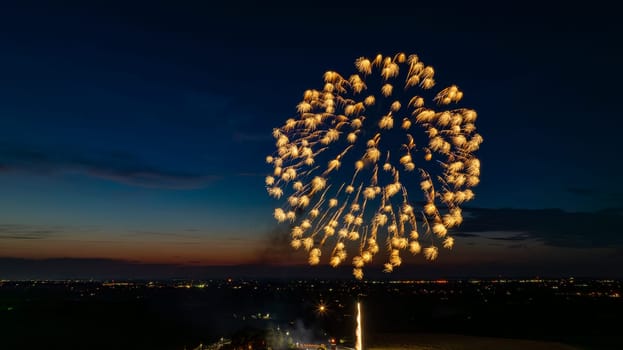 Golden Fireworks Exploding In The Night Sky, Forming A Large, Brilliant Burst Over The Distant City Lights And A Gathered Crowd, With A Twilight Horizon Adding To The Festive Scene.