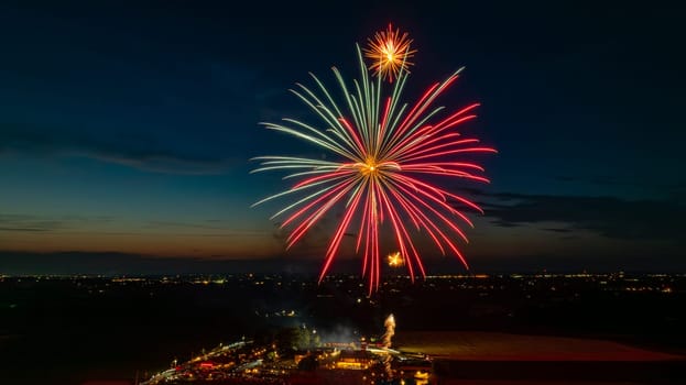 Bright Red And Green Fireworks Exploding In The Night Sky, Casting Vibrant Bursts Over The Distant City Lights And A Gathered Crowd, With A Twilight Horizon Adding To The Festive Atmosphere.