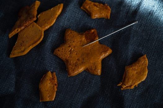 Broken Brown sugar caramel candy cookies with a metal needle in the shape of a star. Concept of survival game