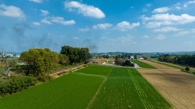 An aerial perspective showcases vibrant fields and farmland, highlighting the rich green crops and the serene landscape under a sunny sky.