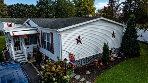 A well-maintained Mobile, Prefab, Manufactured, house features star decorations and a colorful garden, showcasing a cozy atmosphere in a residential area.