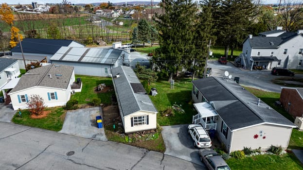 Various Mobile, Prefab, Manufactured, homes are seen in a rural setting with colorful autumn trees and a distant industrial area