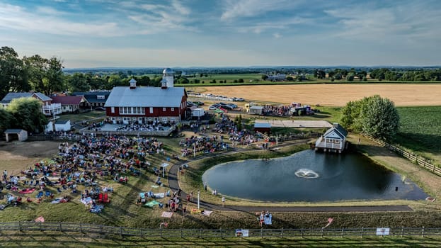 Ronks, Pennsylvania, USA, July 3, 2024 - Aerial View Of A Farm Hosting An Outdoor Event With A Large Crowd, Red Barn, Small Pond, And Scenic Fields.