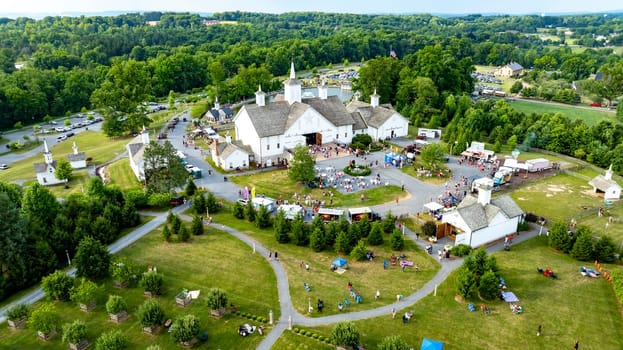 Elizabethtown, Pennsylvania, USA, July 4, 2024 - Charming Rural Fair With White Barns, Small Churches, Food Trucks, And People Enjoying The Festivities Amidst Greenery And Rolling Hills, Creating A Vibrant Community Atmosphere.