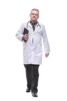 Full length portrait of a smiling male doctor walking towards the camera isolated on white background holding a clipboard