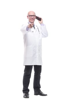 in full growth. smiling doctor with a smartphone. isolated on a white background.