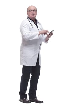in full growth. Mature doctor reading a message on his smartphone. isolated on a white background