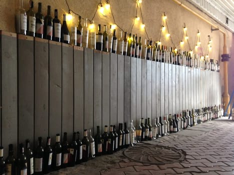 A lot of wine bottles standing under the wall. . High quality photo