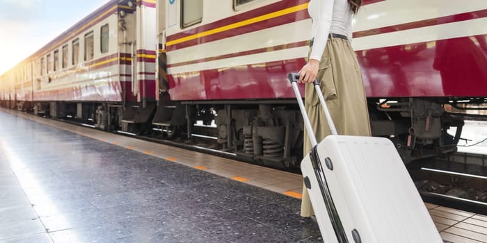 Travel concept at train station, Young Tour woman asian walking dragging luggage suitcase bag. Asian women waiting for train and planning happy holiday vacation.