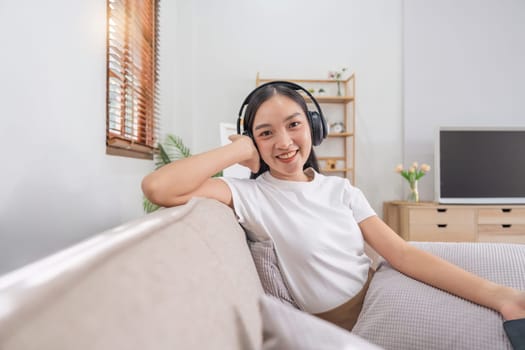 Asian beautiful woman wearing headphone to listen music on smartphone. Lifestyle and leisure concept.