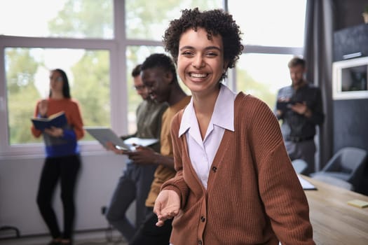 Successful businesswoman standing in creative office and looking at camera while smiling