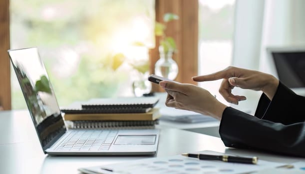 A businessman sits on a smartphone at his desk to check corporate work information..