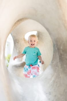 Child playing on outdoor playground. Toddler plays on school or kindergarten yard. Active kid on stone sculpured slide. Healthy summer activity for children. Little boy climbing outdoors