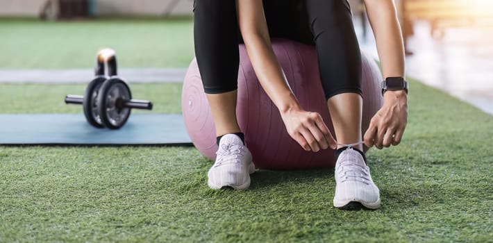 Young woman tying her shoelaces in preparation for exercising at the gym..