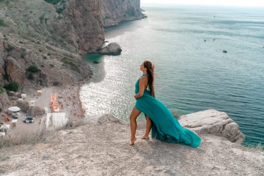 Woman sea trevel green dress. Side view a happy woman with long hair in a long mint dress posing on a beach with calm sea bokeh lights on sunny day. Girl on the nature on blue sky background