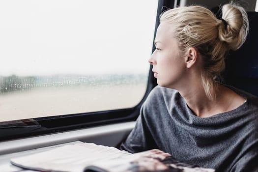 Thoughtful blonde young lady traveling by train.