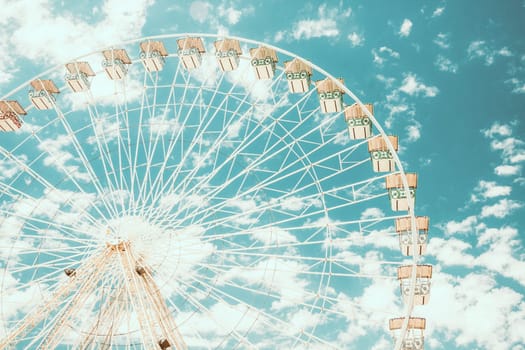 Ferris wheel of fair and amusement park. White clouds in the blue sky in background.