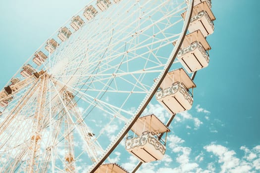 Ferris wheel of fair and amusement park. White clouds in the blue sky in background.