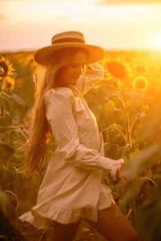 Beautiful middle aged woman looks good in a hat enjoying nature in a field of sunflowers at sunset. Summer. Attractive brunette with long healthy hair