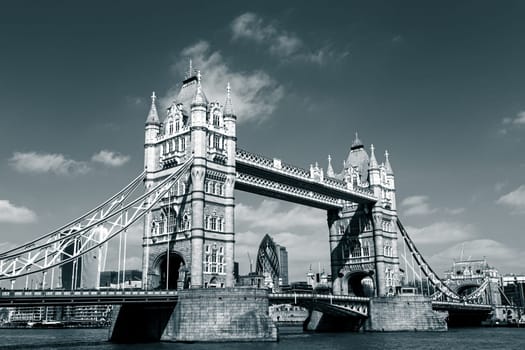 Red traditional double-decker bus driving on Tower Bridge in London, UK. London City skyscrapers in the background.