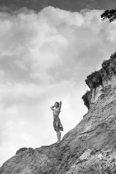 Young woman posing nude and enjoying nature on sand hill against sky background. Nature, beauty and nudity concept