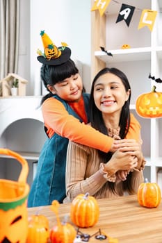A joyful mother and daughter enjoying Halloween festivities with pumpkins and decorations in a cozy home setting.