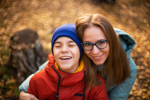 Autumn portrait of happy beautiful woman with her son on fall nature background
