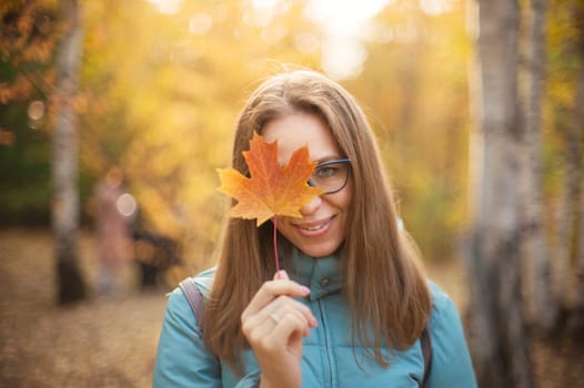 Autumn portrait of beautiful woman with maple leaves on fall nature background