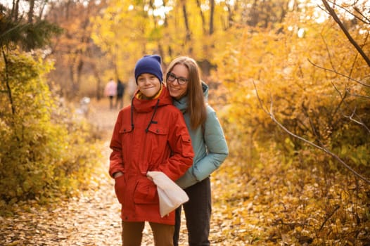 Autumn portrait of happy beautiful woman with her son on fall nature background. Shallow depth of field