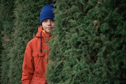 Autumn portrait of boy teen on thuja nature background
