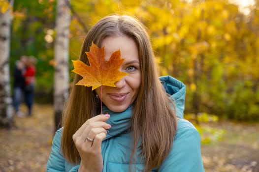 Autumn portrait of beautiful woman with maple leaves on fall nature background