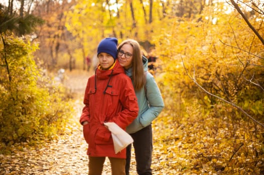 Autumn portrait of happy beautiful woman with her son on fall nature background. Shallow depth of field