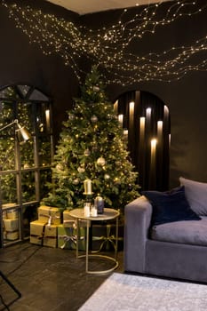 Christmas interior with a beautiful Christmas tree, sofa, light bulbs and dark background