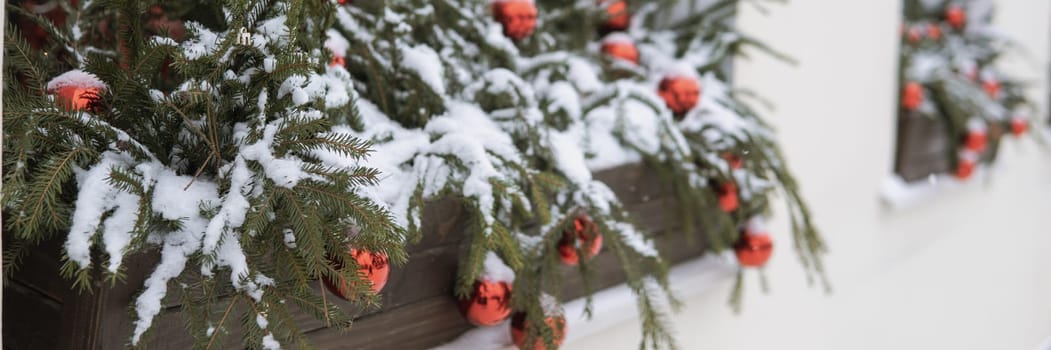 Christmas trees decorated with red balloons in front of the cafe entrance. Street New Year decorations.