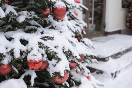 Christmas trees decorated with red balloons in front of the cafe entrance. Street New Year decorations.