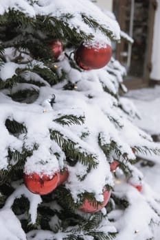 Christmas trees decorated with red balloons in front of the cafe entrance. Street New Year decorations.